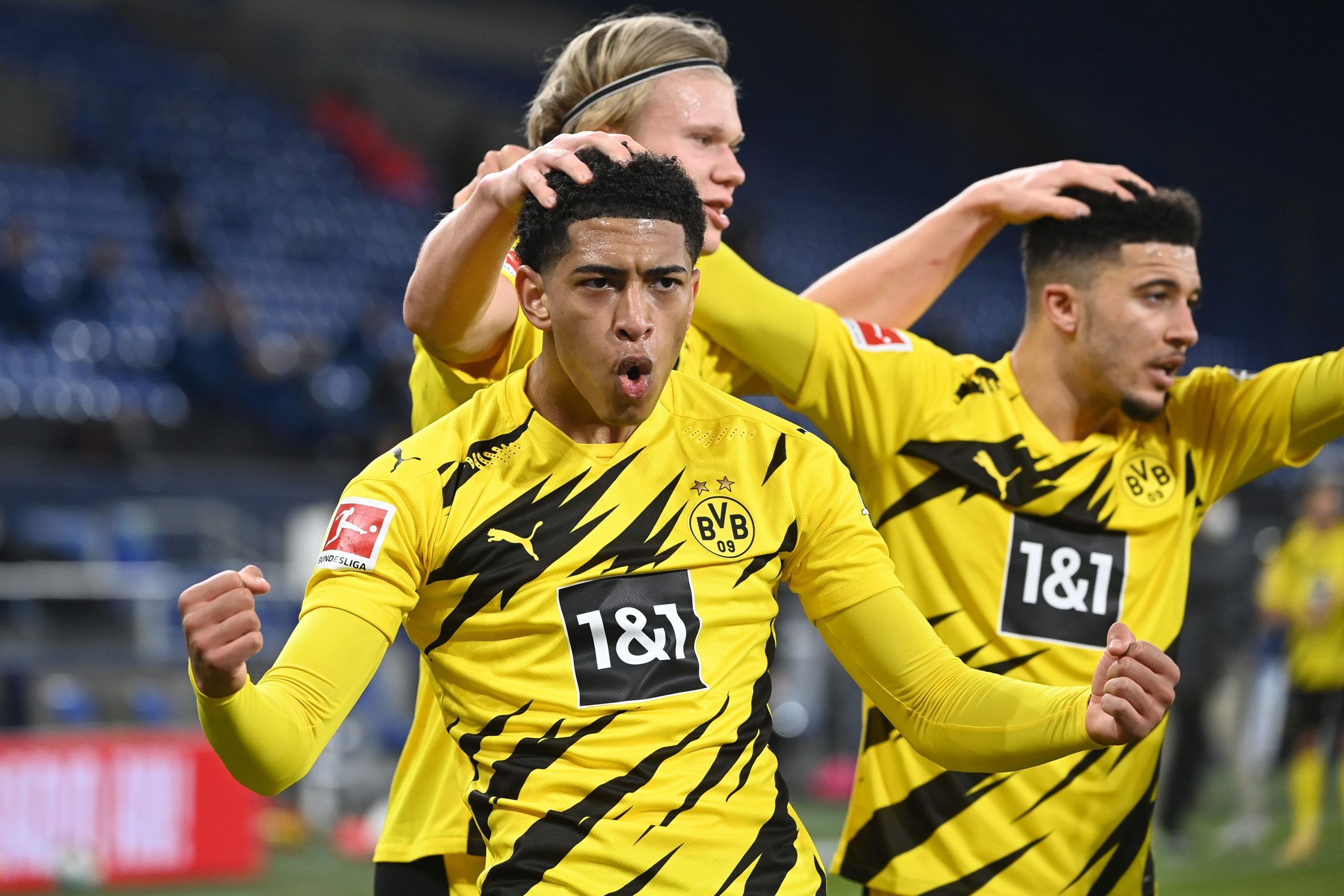 Dortmund's Norwegian forward Erling Braut Haaland (C) celebrates scoring the 4-0 goal with Dortmund's English midfielder Jude Bellingham (L) and Dortmund's English midfielder Jadon Sancho during the German first division Bundesliga football match FC Schalke 04 vs Borussia Dortmund in Gelsenkirchen, western Germany, on February 20, 2021.