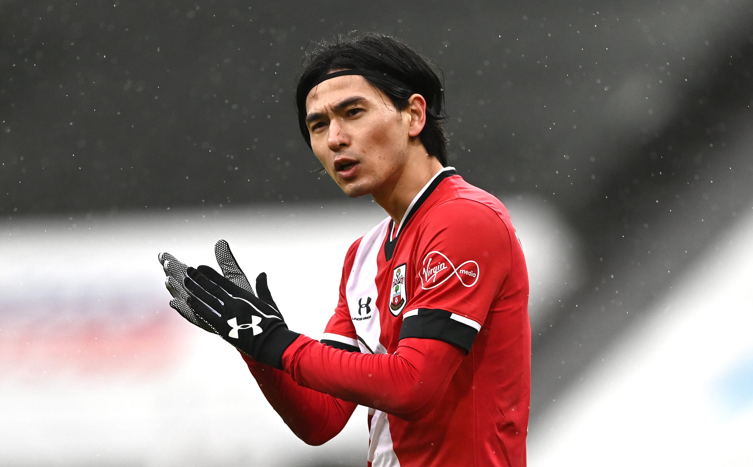 NEWCASTLE UPON TYNE, ENGLAND - FEBRUARY 06: Southampton player Takumi Minamino wearing gloves, gestures during the Premier League match between Newcastle United and Southampton at St. James Park on February 06, 2021 in Newcastle upon Tyne, England.